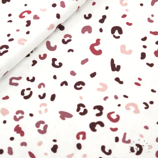 Detailansicht des French Terry Stoffs „Berry Leo“ mit handgemaltem Leo-Muster in Beerentönen auf cremeweißem Hintergrund
