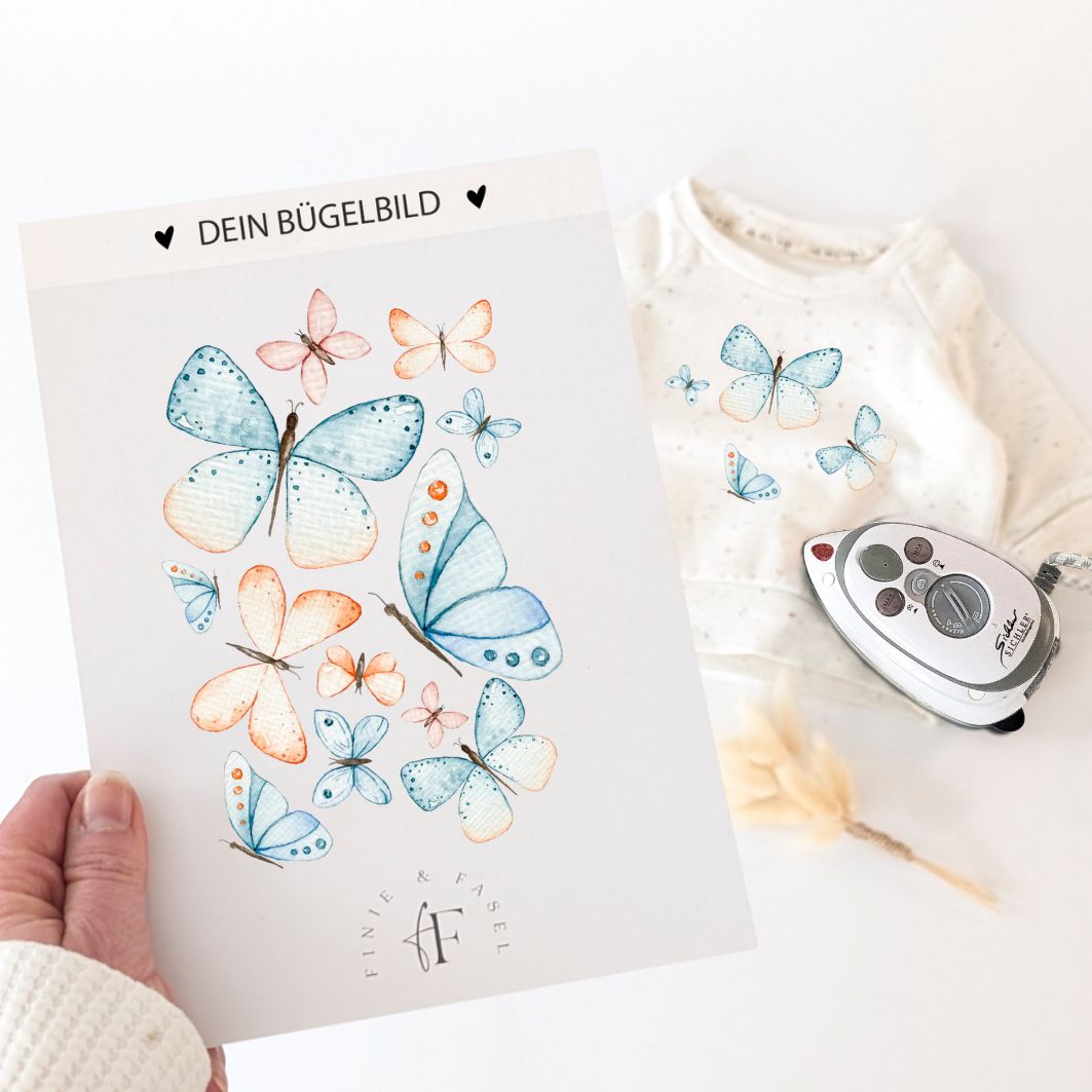 Bügelbild mit handgemalten Schmetterlingen in sanften Farben, daneben ein Pullover mit aufgebügeltem Motiv – ideal zum Personalisieren von Kinderkleidung.